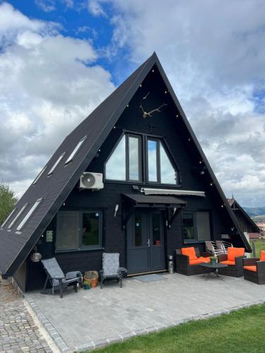 a black house with a pitched roof with a patio at Cabana A Toplita in Topliţa