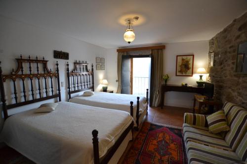 Quinta da Veiga في Covas do Douro: غرفة نوم بسريرين واريكة