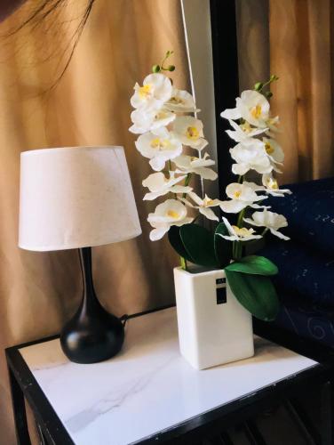 a table with a lamp and a vase of white flowers at RICHVILLE LITTLE BORACAY GUEST HOUSE in Calatagan