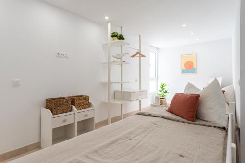 a white bedroom with a bed and a shelf at Sunset in Maspalomas