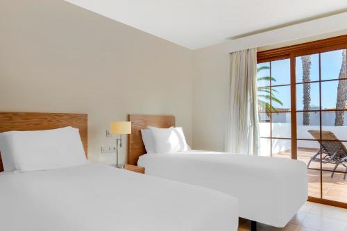 two beds in a hotel room with a balcony at Royal Tenerife Country Club in San Miguel de Abona
