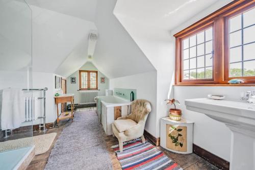 a bathroom with a sink and a chair and a tub at Amazing Arts & Crafts House in Robertsbridge