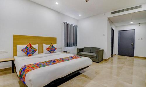 a bedroom with a large bed and a chair at FabHotel Premium Kashi in Varanasi