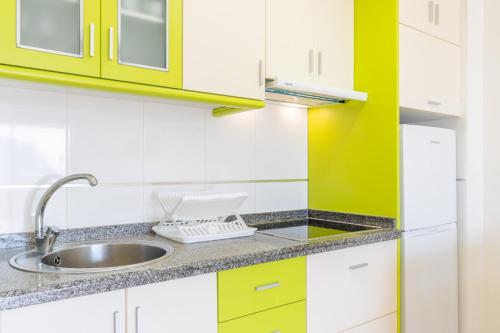 eine Küche mit gelben und weißen Schränken und einem Waschbecken in der Unterkunft Esmeralda13 de Calpe in Calpe