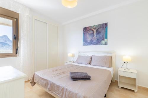 ein weißes Schlafzimmer mit einem Bett und einem Gemälde an der Wand in der Unterkunft Esmeralda13 de Calpe in Calpe