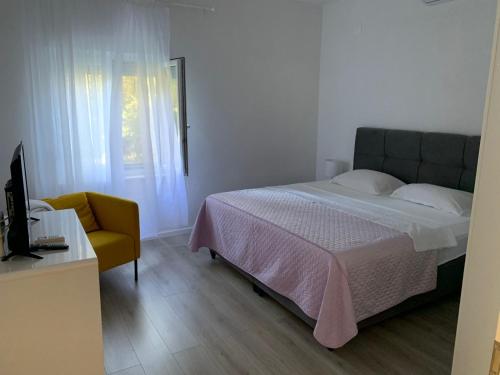 a bedroom with a bed and a chair and a television at Apartment 877-3 in Bibinje