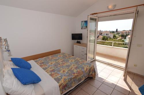 1 dormitorio con 1 cama con almohadas azules y balcón en Apartments house Mai with pool Poreč, en Poreč