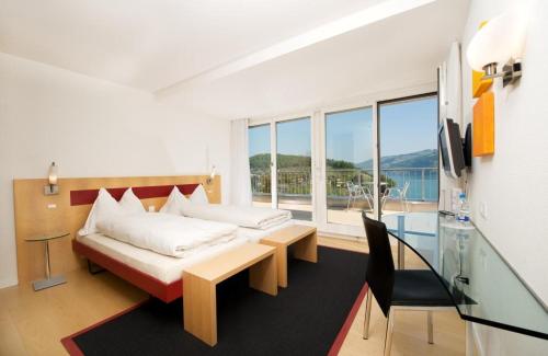 Schlafzimmer mit einem Bett, einem Tisch und einem Fenster in der Unterkunft Hotel Seaside in Spiez