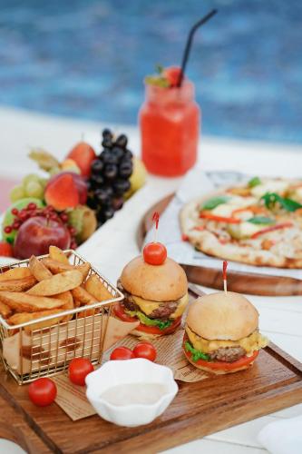 two sandwiches and french fries on a table with food at Metropolitan Al Mafraq Hotel in Abu Dhabi