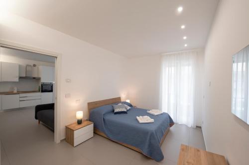a white bedroom with a bed and a kitchen at A casa di Fiore, holiday home in Giovinazzo