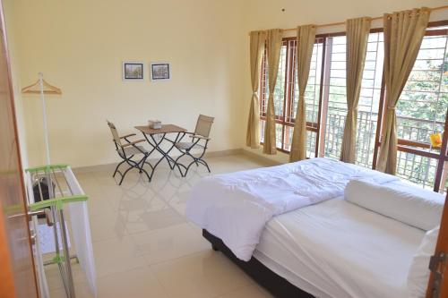 1 dormitorio con 1 cama y 1 mesa con sillas en Kerinci Hill Holiday Home, Dago Golf (for families only), en Bandung