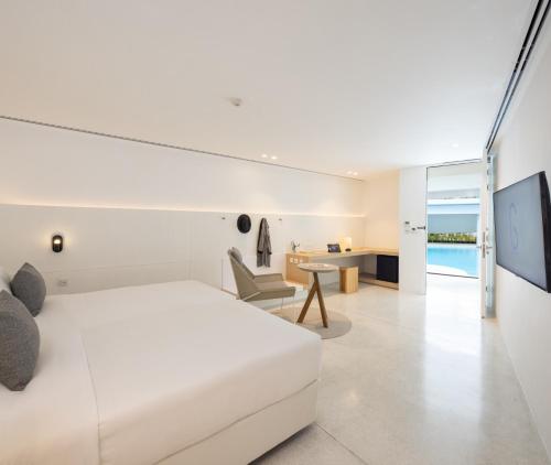 a bedroom with a white bed and a desk at G Nimman Chiang Mai in Chiang Mai