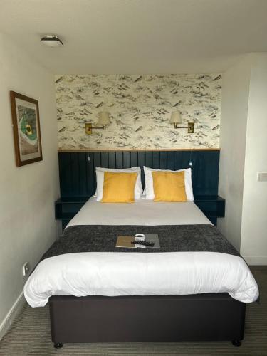 a bedroom with a large bed with yellow pillows at Anchor Inn by Greene King Inns in Beer