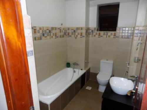 a bathroom with a tub and a toilet and a sink at Comfort Silverline Apartments in Kampala