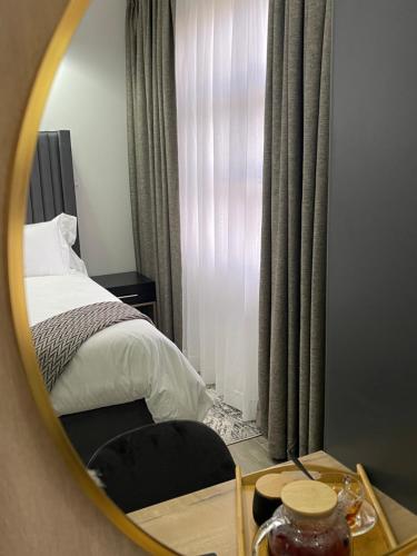 a mirror reflecting a bedroom with a bed and a window at Mayswood Self Catering Apartments in Gaborone