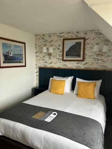 a bedroom with a large bed with yellow pillows at Anchor Inn by Greene King Inns in Beer