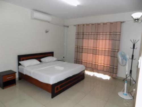 sypialnia z łóżkiem i oknem w obiekcie Comfort Silverline Apartments w mieście Kampala