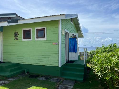 a green tiny house with a blue door at Waves Villa Guesthouse in Kingstown