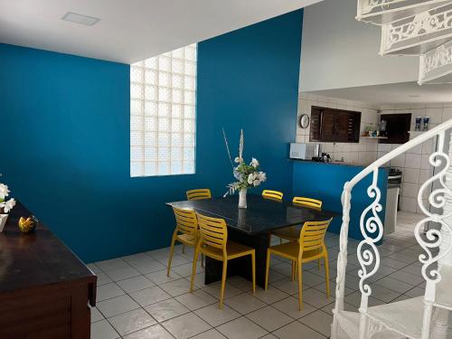 ein Esszimmer mit einer blauen Wand sowie einem Tisch und Stühlen in der Unterkunft CASA DE PRAIA PEROBA in Maragogi