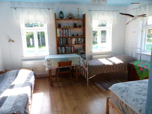 ein Schlafzimmer mit einem Tisch, einem Bücherregal und Fenstern in der Unterkunft Zielony Domek Plutycze in Plutycze