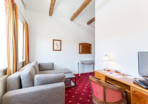 a living room with a couch and a desk at Stadthotel Kramer in Villach