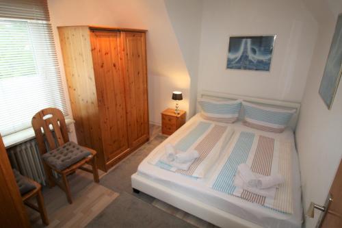 a bedroom with a bed with a chair and a window at Nord-Strand in Norden