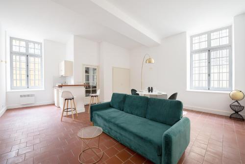 un salon avec un canapé vert et une cuisine dans l'établissement superbe appartement avec cour dans la bastide, à Carcassonne