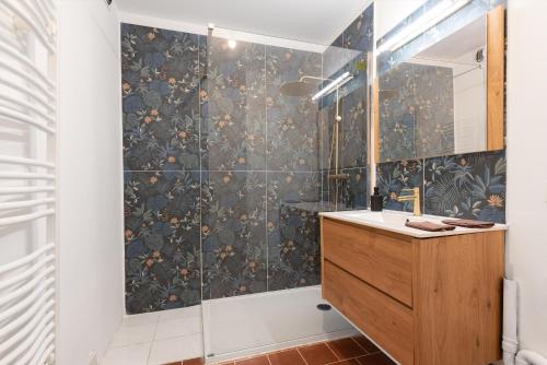 une salle de bain avec une douche avec un lavabo et un miroir dans l'établissement superbe appartement avec cour dans la bastide, à Carcassonne