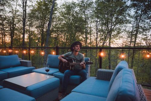 a man sitting on a couch playing a guitar at Bellaria with SPA near Mercier Lake in La Conception