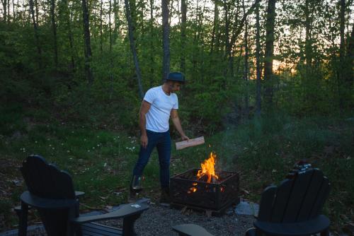 a man standing by a fire with a box at Bellaria with SPA near Mercier Lake in La Conception