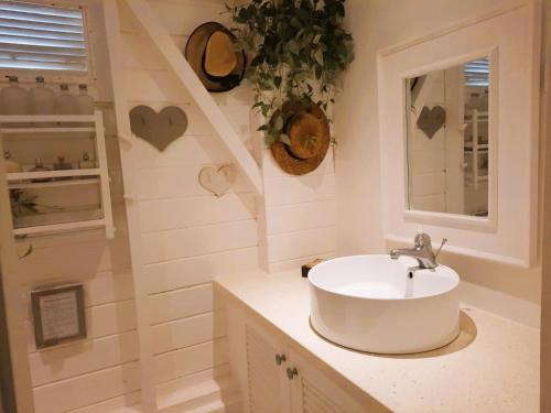 baño blanco con lavabo y ventana en Les Gîtes de Bergette, en Petit-Bourg