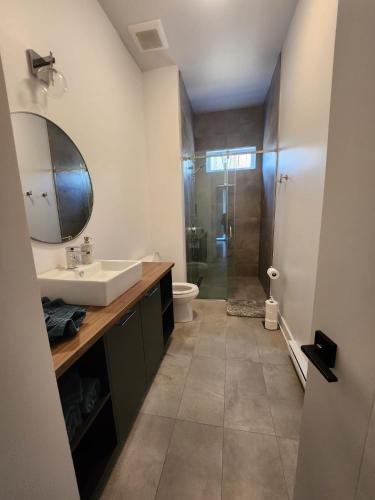 a bathroom with a sink and a toilet and a mirror at Bellaria with SPA near Mercier Lake in La Conception
