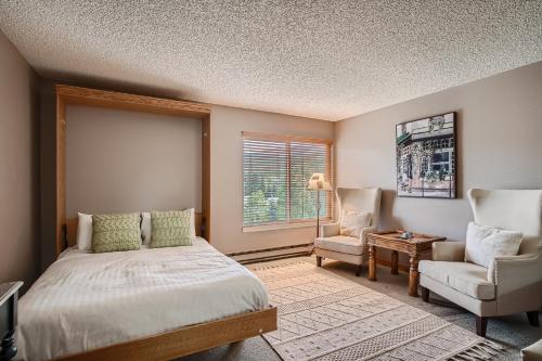 a bedroom with a bed and a chair and a window at Blazing Saddles #122 in Breckenridge