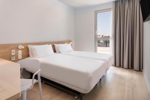 a white bedroom with a bed and a window at B&B HOTEL Lleida in Lleida