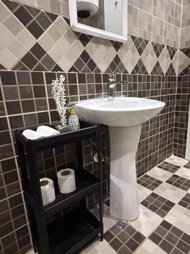 La salle de bains est pourvue d'un lavabo et d'une étagère avec des serviettes. dans l'établissement شقة luxury في شمال الرياض الصحافة, à Riyad