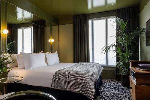 a hotel room with a bed and two windows at Hôtel La Conversation in Paris