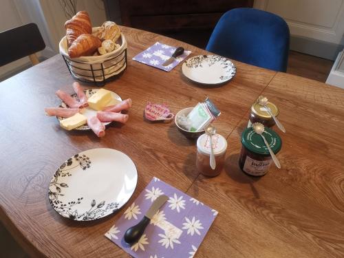 una mesa con platos de comida y una cesta de pan en La maison aux rosiers, en Montmarault
