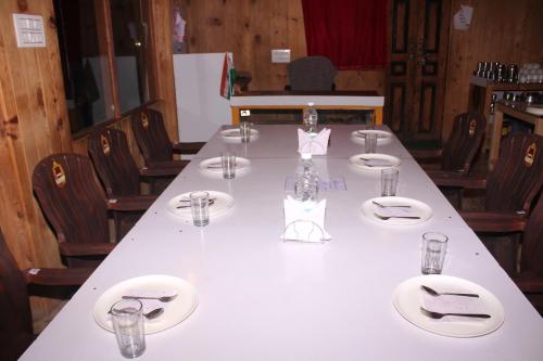 a long white table with plates and glasses on it at Hotel Mannat Sach Pass in Tisa