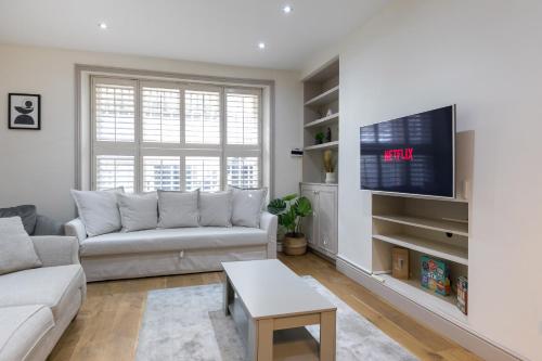 een woonkamer met een bank en een tv bij The Notting Hill Residence - 2 BR Apartment Close to Hyde Park in Londen