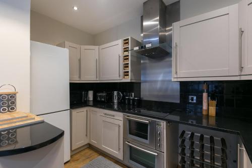 een keuken met witte kasten en zwarte aanrechtbladen bij The Notting Hill Residence - 2 BR Apartment Close to Hyde Park in Londen