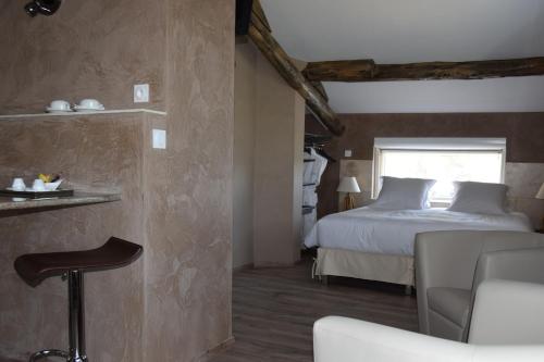 a bedroom with a bed and a chair in a room at Résidence hôtelière et SPA des sources du gros noyer in Malaucène