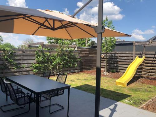 a patio with a table and an umbrella and a slide at Central Oasis near Brussels / Airport in Kortenberg