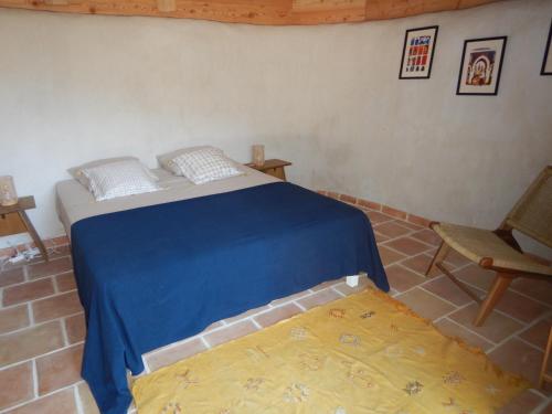 a bedroom with a bed with a blue blanket and a chair at SAWUBONA in Les Adrets de l'Esterel