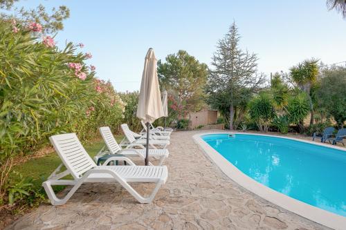 a row of chairs and an umbrella next to a swimming pool at Casa do Vale in Sao Pedro de Tomar