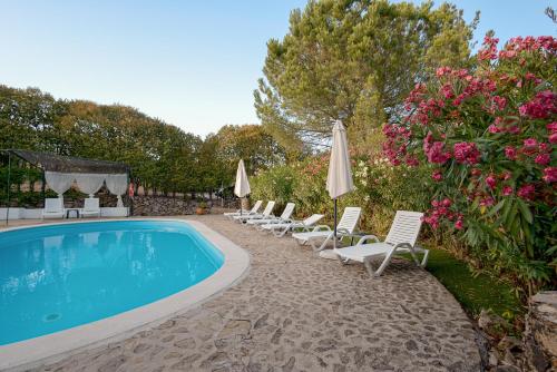 - un groupe de chaises longues et de parasols à côté de la piscine dans l'établissement Casa do Vale, à Sao Pedro de Tomar