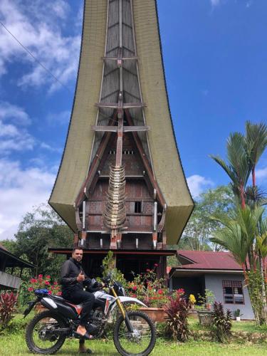 a man sitting on a motorcycle in front of a church at Toraja Homestay & Coffee Bunna in Rantepao