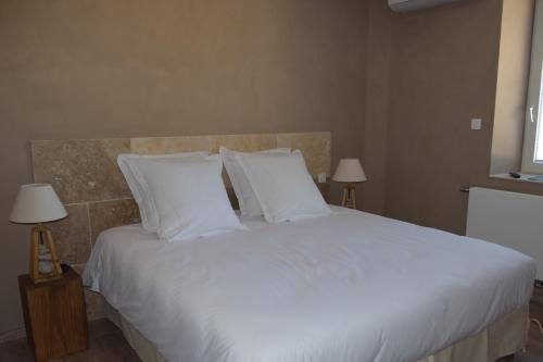 a bedroom with a large white bed with white pillows at Résidence hôtelière et SPA des sources du gros noyer in Malaucène
