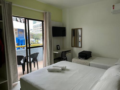 a bedroom with two beds and a balcony with a desk at Pousada Villa Atlântica in Balneário Camboriú