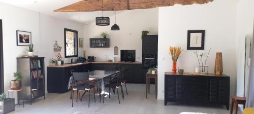 a kitchen with black cabinets and a table and chairs at La villa du pressoir, classé 3 étoiles meublé de tourisme in Le Pallet