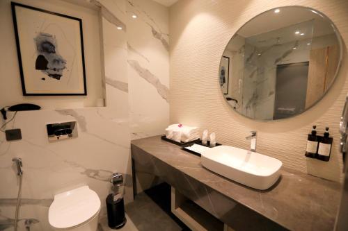 a bathroom with a sink and a mirror and a toilet at Regenta Place Amritsar by Royal Orchid Hotels Limited in Amritsar